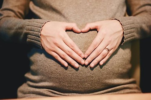 pregnant woman's belly with hands forming a heart