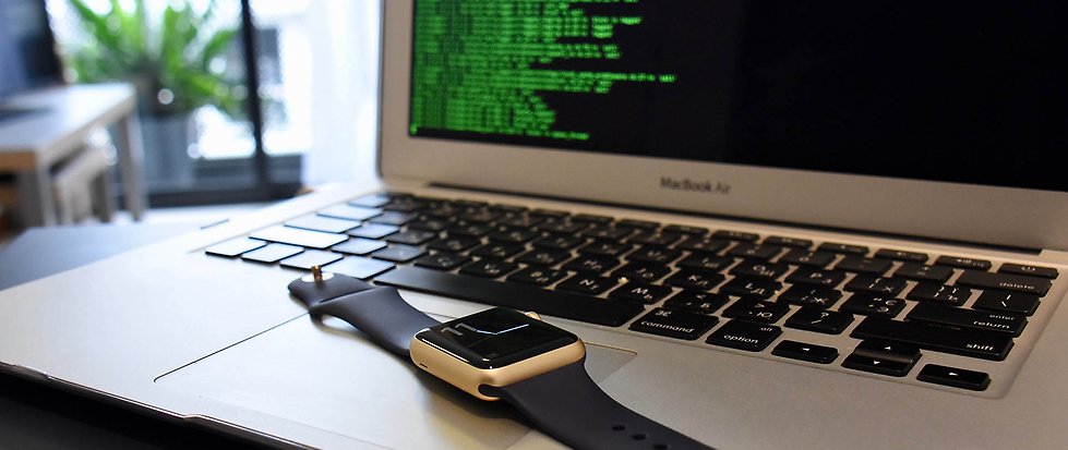 Laptop på ett skrivbord med en armbandsklocka på tangentbordet