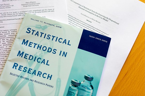 En bok i statistiska metoder inom medicinsk forskning ligger ovanpå två vetenskapliga artiklar på ett bord
