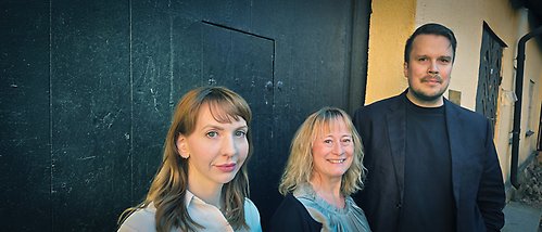 A group photo of three people looking into the camera. They appear to be happy.