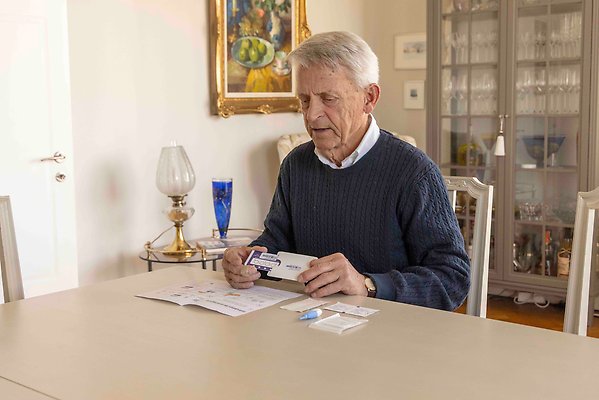 A man who is looking at the contents of the home sampling kit that are placed on the table in front of him
