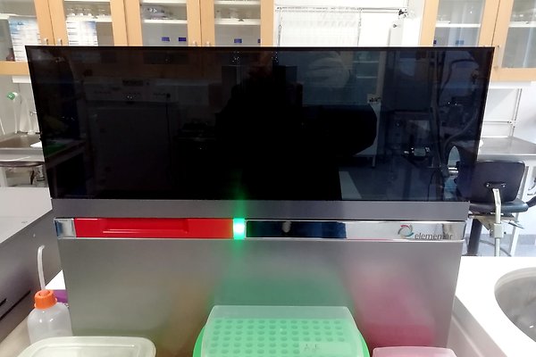 Spektrometer precisION från Elementar. Den ser ut som en fyrkantig låda med en nedre del i metall och en övre del i glas. En grön lampa lyser på framsidan. Provlådorna står framför spektrometern.