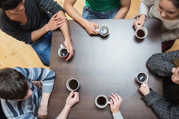 Individer sitter runt ett bord och dricker kaffe